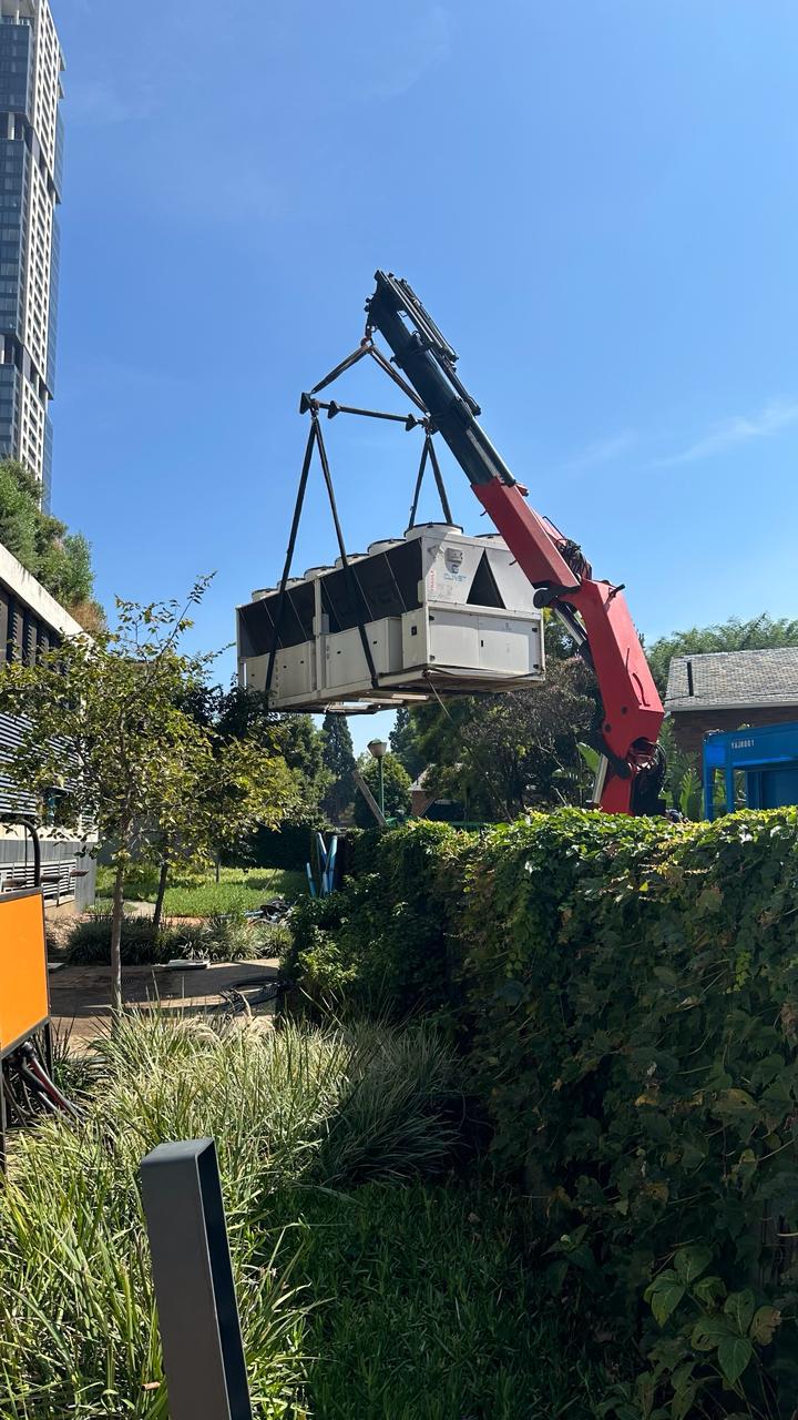 Air-cooled chiller lifted into position by crane.