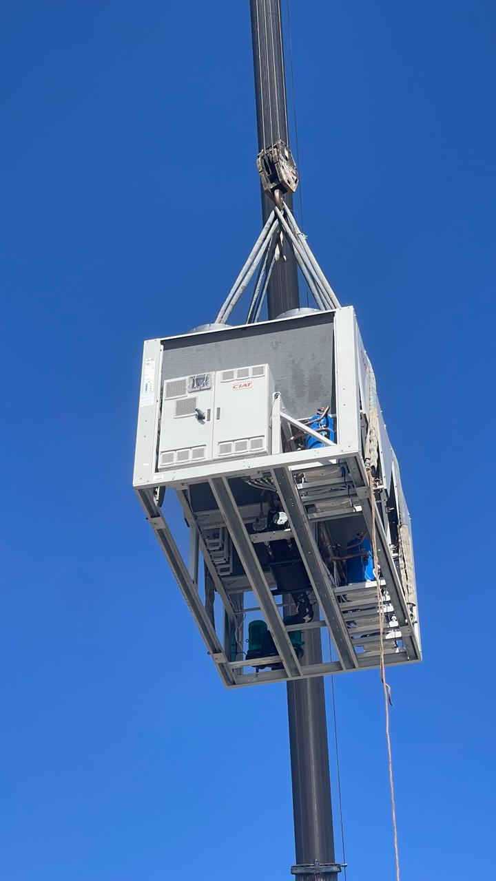 Air-cooled chiller lifted to the roof by crane.