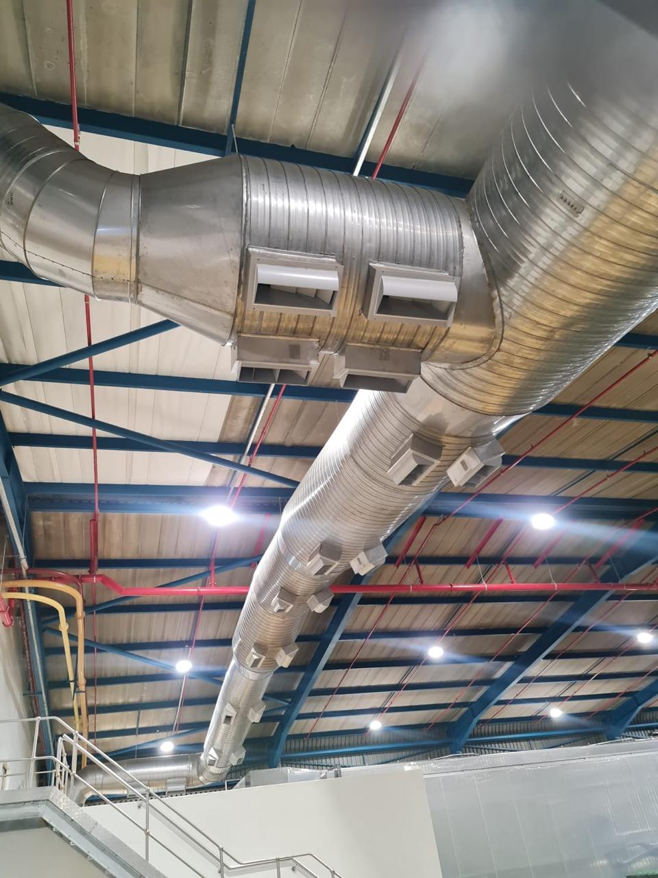 Spiral ducting with diffusers along a warehouse work area.