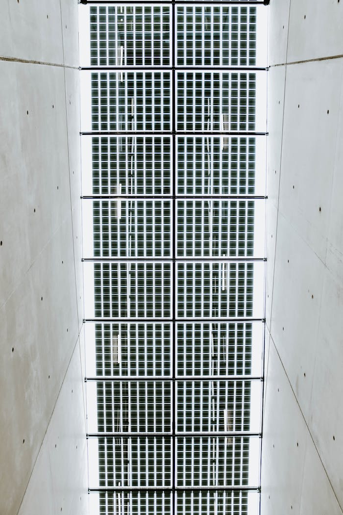 Abstract view of a modern ceiling with glass panels and metal grills in a hallway.